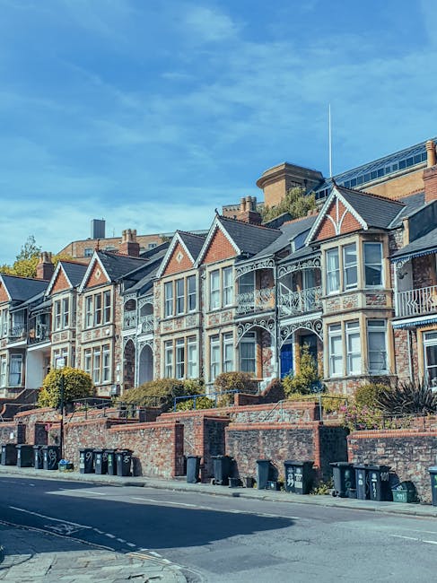 A street scene in Hammersmith featuring a row of Victorian-style terraced houses with red brick facades, white window frames, and decorative architectural details, situated on the left side of the ima
